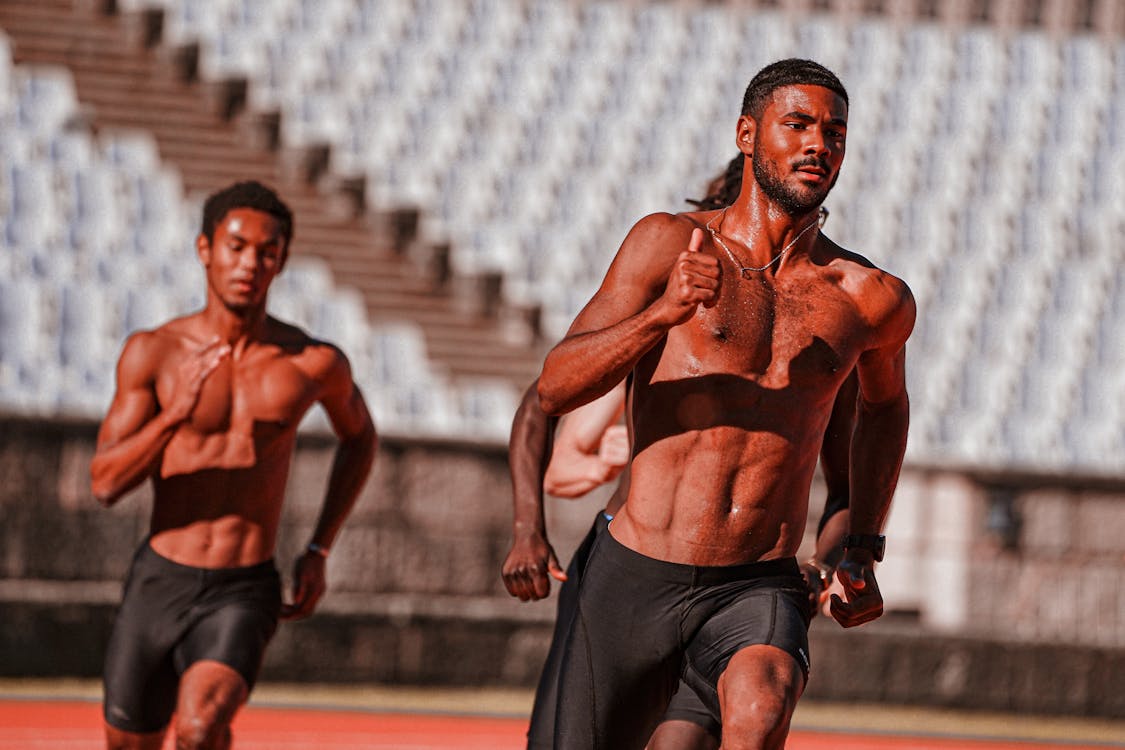 Free Men Running on Running Track Stock Photo